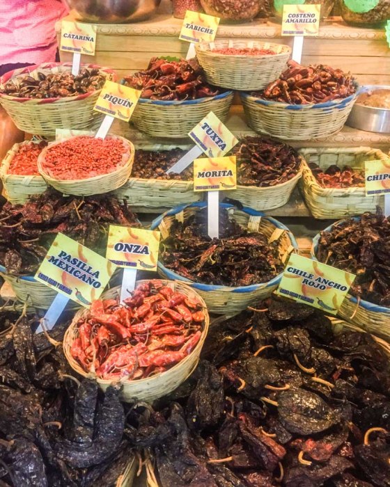 A vibrant street food scene in Oaxaca, showcasing tlayudas being prepared with various toppings.