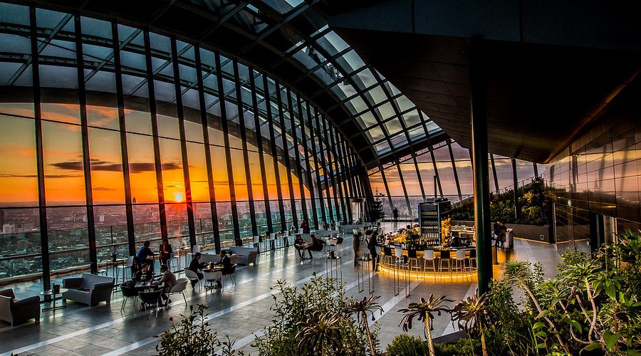 A wide-angle shot from inside the Sky Garden, showcasing the city skyline, particularly at sunset