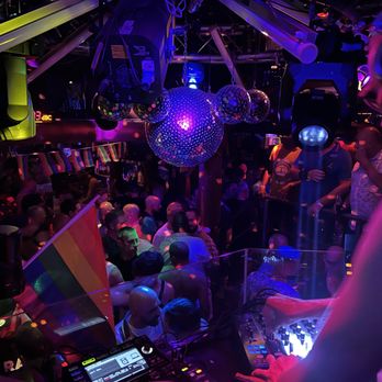 A group of people laughing and raising their glasses in a crowded bar. The image captures the lively social atmosphere of the hostel and the pub crawl.