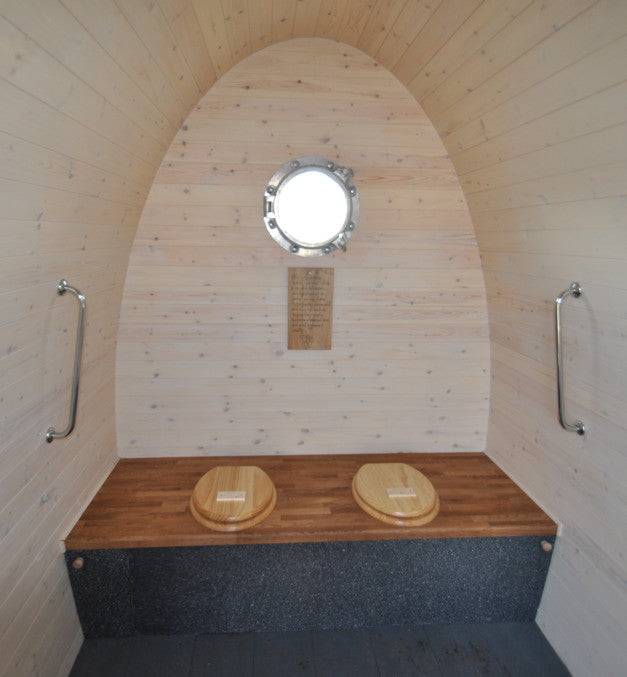 Close-up shot of the black plastic composting bins being installed inside the wooden structure, emphasizing the accessibility of the bins and the space for adding materials