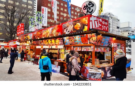 Close-up of Aiko Tanaka's intricate ice carving of a Hokkaido Brown Bear at the Sapporo Snow Festival, with blurred background of festival-goers, emphasizing the detail of the art and the atmosphere of the festival
