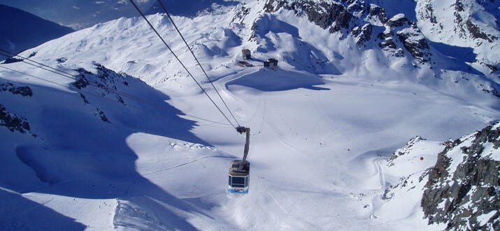 A paraglider soars over Interlaken with snow-covered mountains in the background