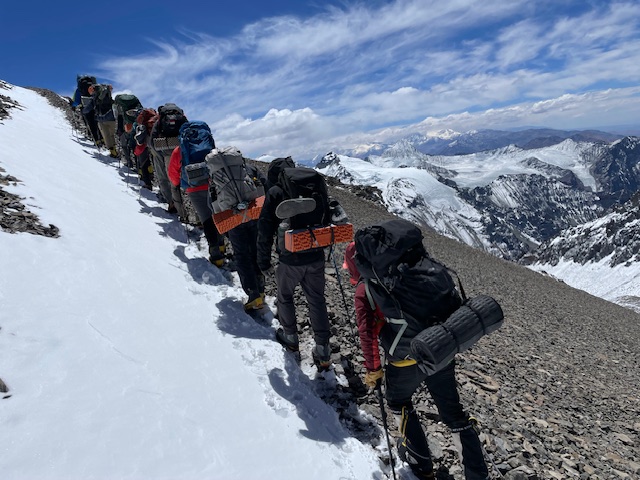 Climbers ascending a steep, snow-covered slope on Aconcagua, highlighting the harsh environment and their determination.