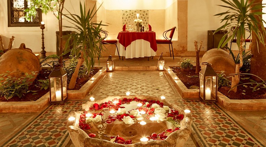 Silver teapot pouring mint tea. The teapot has a classic Moroccan design. The setting is a rooftop restaurant.