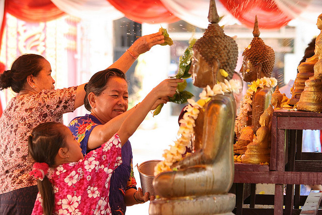 A vibrant parade in Luang Prabang during Boun Pi Mai Lao, with people splashing water and celebrating.