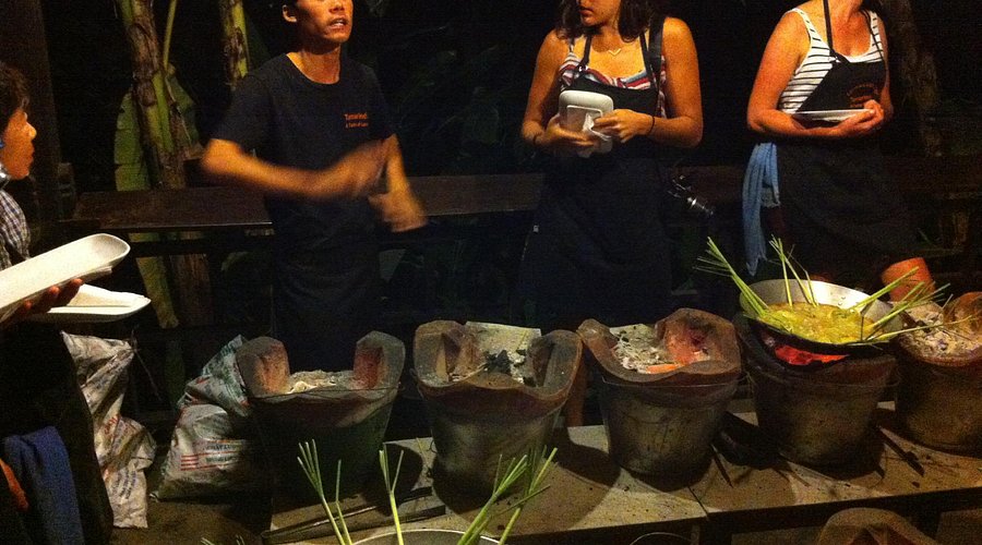 Line of monks in saffron robes during Tak Bat in Luang Prabang, locals kneeling and offering alms, captured with shallow depth of field