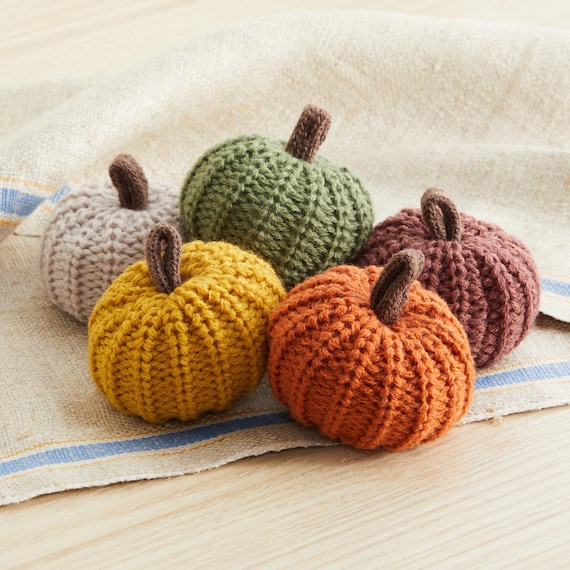 A collection of cozy throw pillows covered in flannel fabric in various autumn patterns and colors, arranged on a sofa