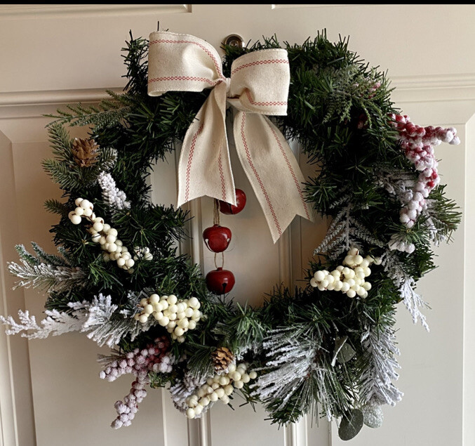 Dried orange slices being added to the evergreen wreath, illustrating the incorporation of natural citrus elements.
