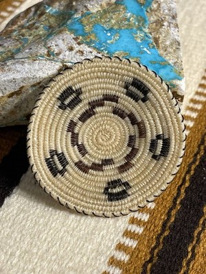 A Tohono O'odham artisan weaving a basket with intricate designs, showcasing the traditional techniques and the artistry involved in creating these unique cultural items, demonstrating the deep connection between the artisan and the Sonoran Desert landscape.