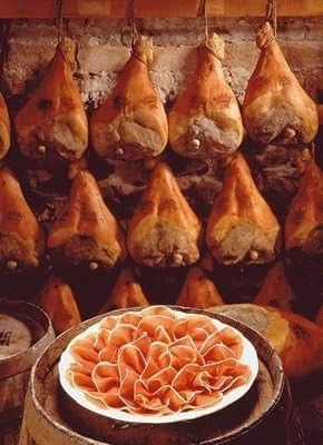 A photograph of hams hanging in rows in a Prosciutto di Parma curing facility, showcasing the traditional curing process and the scale of production, highlighting the unique environment necessary for creating authentic Prosciutto di Parma.