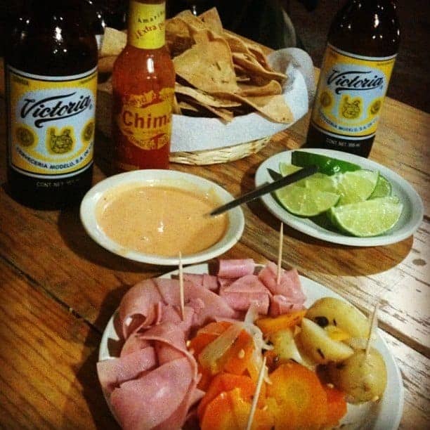 An oversized, crispy Tlayuda topped with various ingredients like beans, cheese, avocado, and meat.