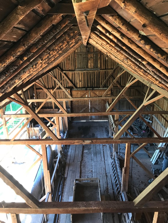 A close-up of a craftsman repairing a large wooden barn beam.