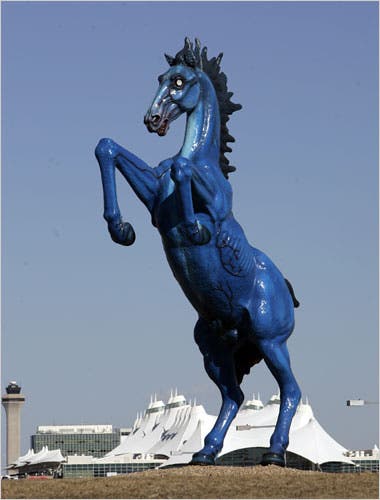 A head-on view of the Blue Mustang statue, highlighting its imposing size and piercing red eyes.