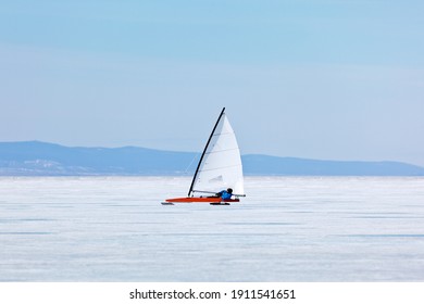 Wide shot of an ice-sailer with a bright sail on the vast expanse of Lake Baikal, with mountains in the background, capturing the scale and serenity of the landscape.