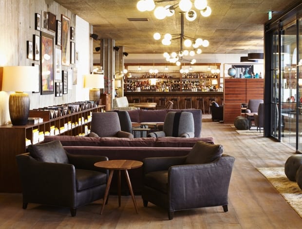 The lobby of The Hoxton, Chicago, showcasing its upcycled furniture, reclaimed wood accents, and artwork made from recycled materials, highlighting the hotel's commitment to sustainable design