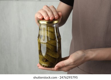 Woman holding jar pickled cucumbers