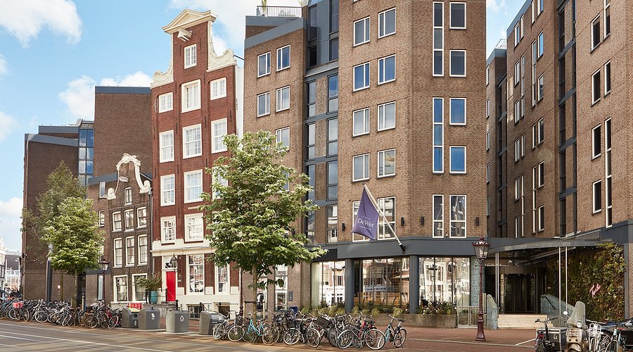 A cozy room at The Dylan Amsterdam featuring rich fabrics, a comfortable bed, and a canal view