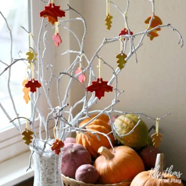 Close-up of colorful clay leaves hanging on a bare branch, showing a creative variation of the Thankful Tree concept