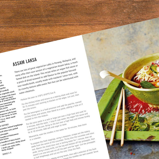 A close-up shot of Assam Laksa broth being ladled into a bowl, highlighting the bits of mackerel and herbs