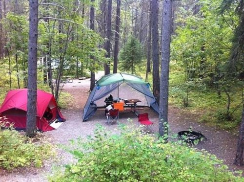 A family setting up a large tent at a campsite.