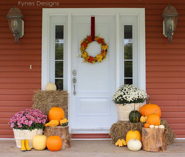 A beautifully decorated fall front porch with pumpkins, gourds, mums, and other fall decor