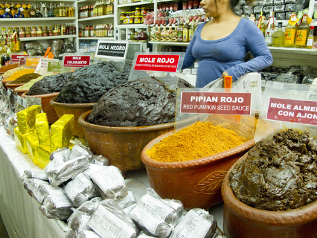 A vibrant overhead shot of a market stall overflowing with dried chiles, spices, and other Mole ingredients