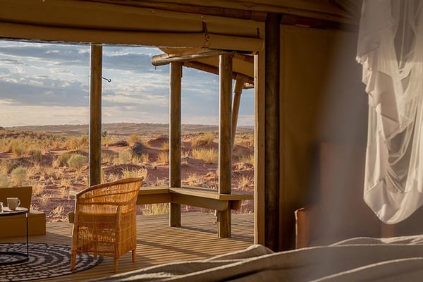 Wolwedans Dunes Lodge. A series of tented chalets blend seamlessly into the surrounding sand dunes. The structures are made of natural materials, creating a harmonious connection with the desert landscape.