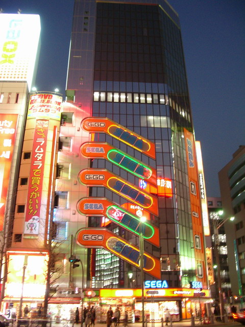 An image of a Japanese PC gamer looking frustrated while reading a news article on their computer screen. The article is about the closure of Tango Gameworks. The room is dimly lit, and the gamer is wearing headphones. Technical details: Medium resolution, natural lighting, focus on the gamer's facial expression. Mood: Angry and disappointed. Composition: Close-up shot, capturing emotion.