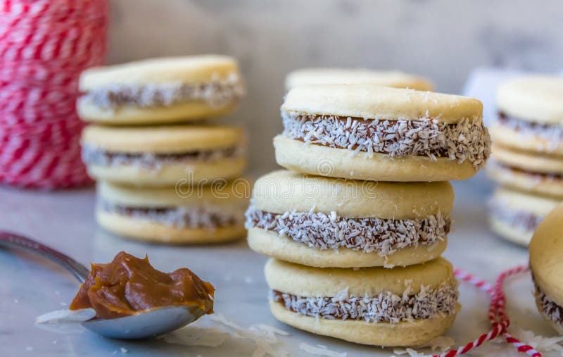 A wide-angle shot of a table at Havanna, focusing on the alfajores and a cup of coffee, with a scenic view of the Buenos Aires skyline visible through the café window during the golden hour.