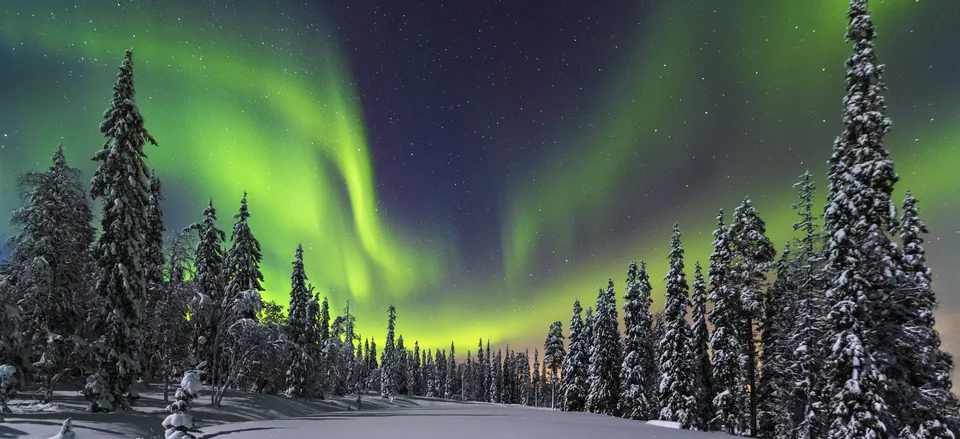 Two people snowshoeing under the Aurora Borealis in Lapland