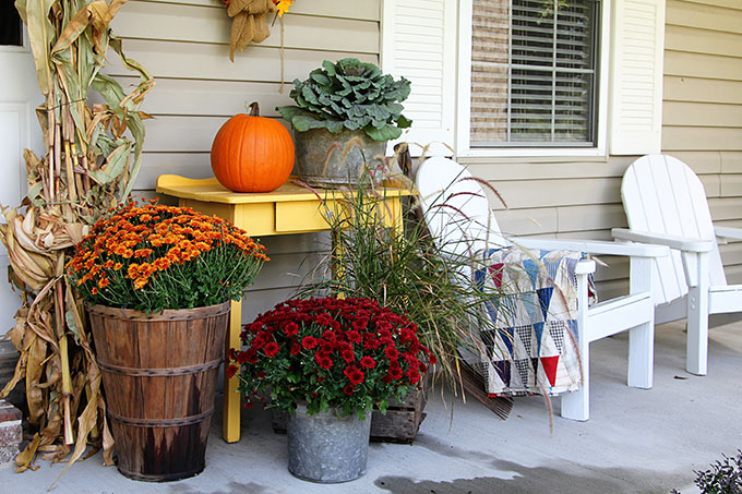 a fall porch with blankets, pillows, and other cozy elements