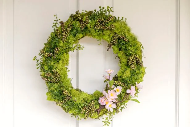 A partially completed dried herb wreath with various herbs and flowers attached to the grapevine form.