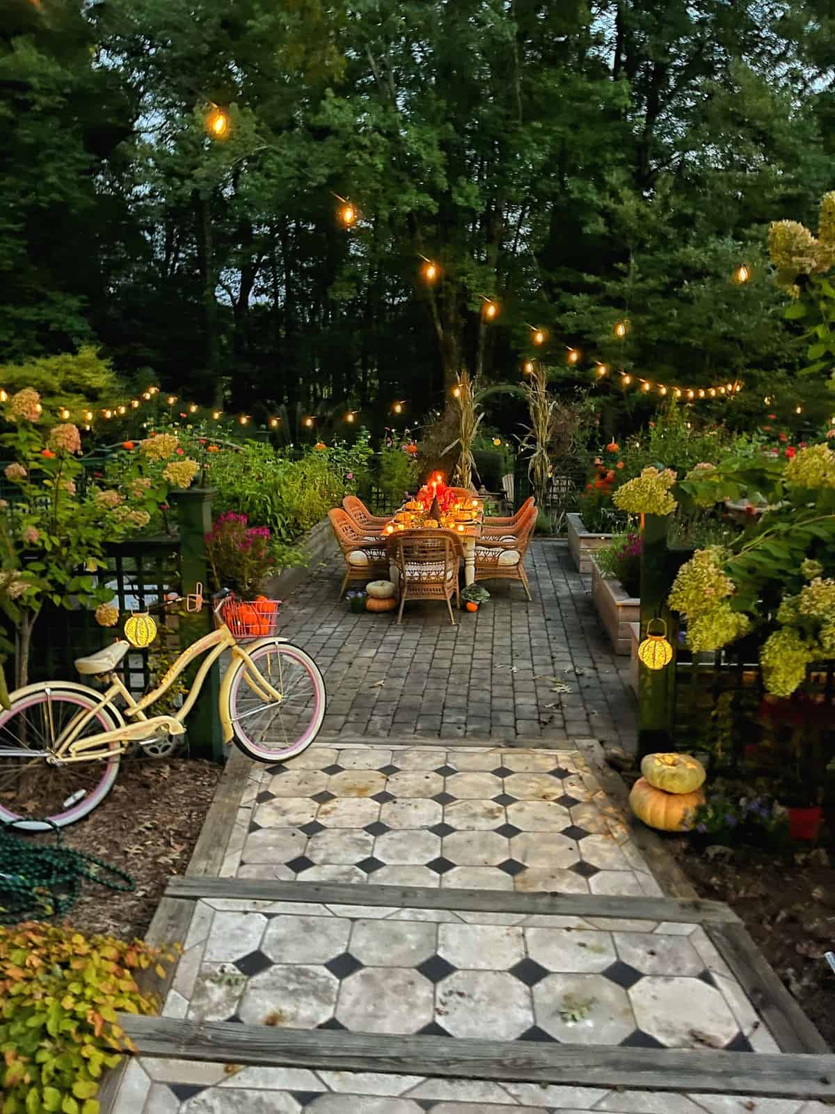 cozy farmhouse porch decorated with pumpkins, gourds, and string lights, with a garden in the background