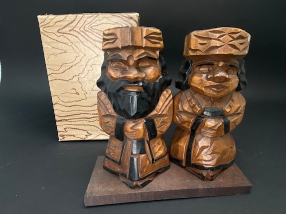 A brightly lit ice sculpture at night with snow gently falling